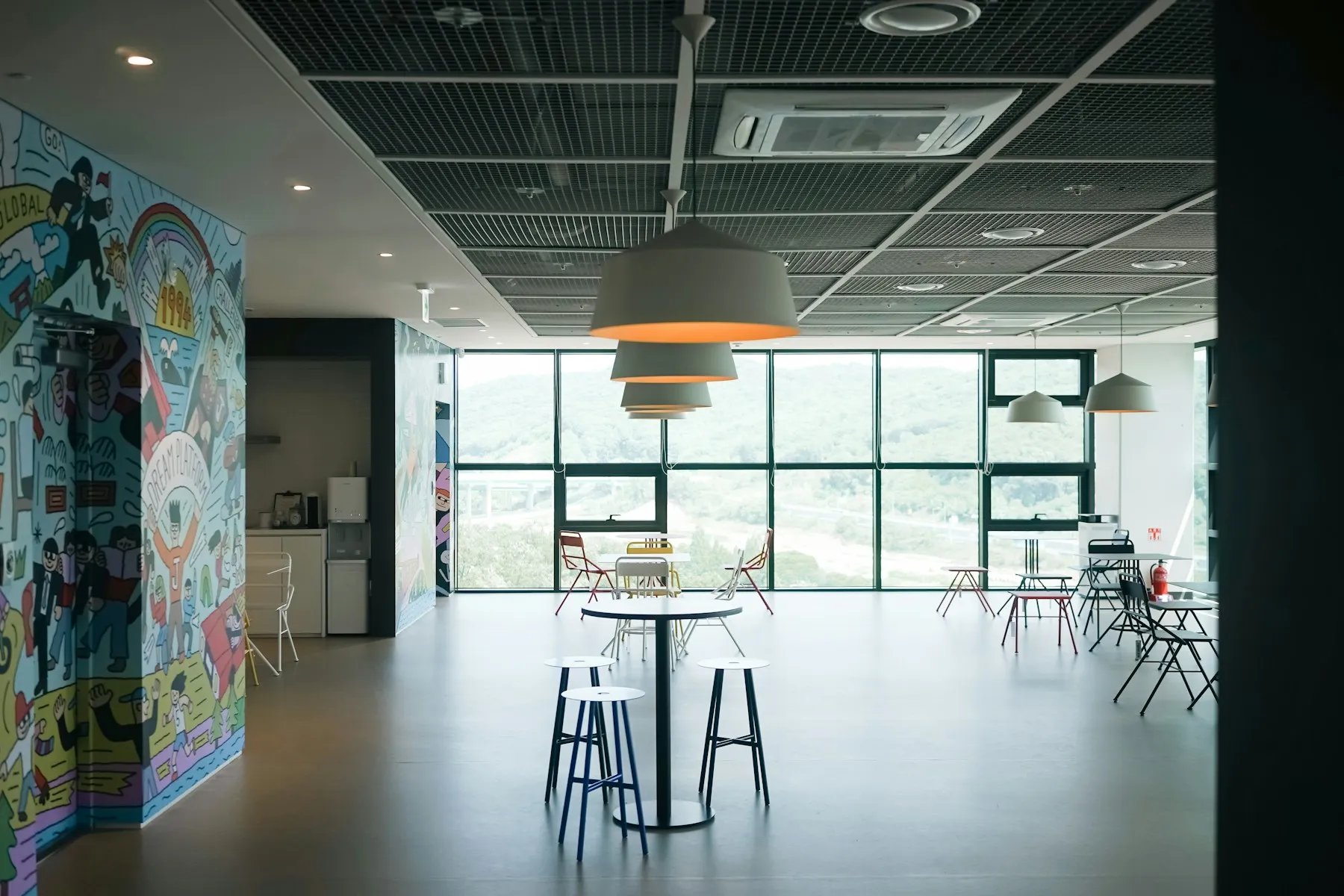 A light-filled shared office café with playful illustrations painted across its walls.